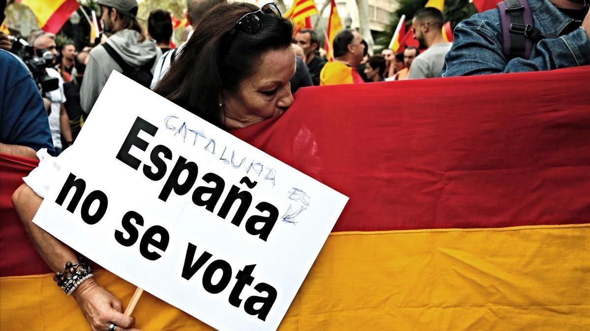 Una participante en la manifestación en contra del referéndum de la plaza Urquinaona besa una bandera de España.