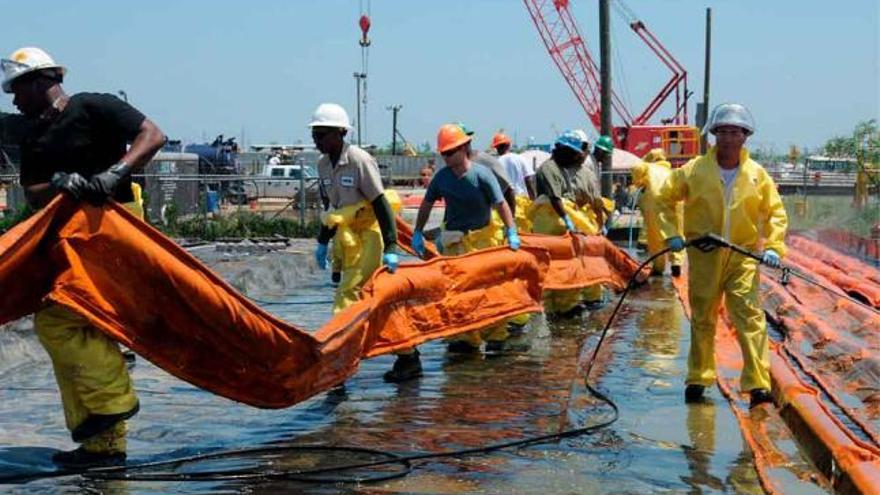 Trabajadores arrastran una de las barreras para frenar el avance del crudo hacia la costa, en la localidad norteamericana de Venice.