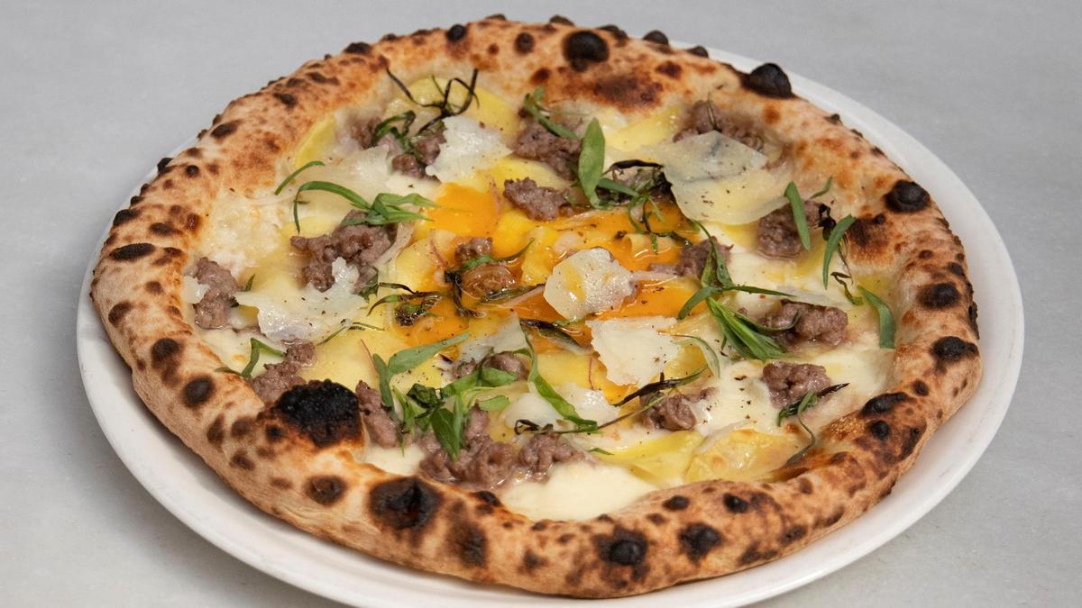 Pizza de ternera criada por Petramora y ahumada Rooftop Smokehouse con 'fior di latte', queso fontina, patata, cebolla, pecorino, yema de huevo y aceite cítrico de estragón, una de las novedades de Parking Pizza..