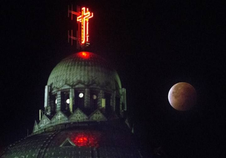 The dome of the Koekelberg Basilica is seen while the moon turns orange during a total "supermoon" lunar eclipse in Brussels