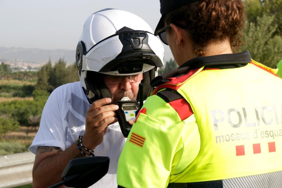 Una agent dels Mossos d'Esquadra sotmet a la prova d'alcoholèmia un motorista.