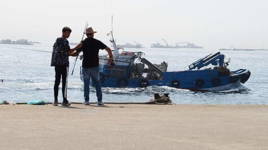 Dos pescadores observan el trabajo en las bateas para agrupar en sacos el mejillón grande. // G. Núñez