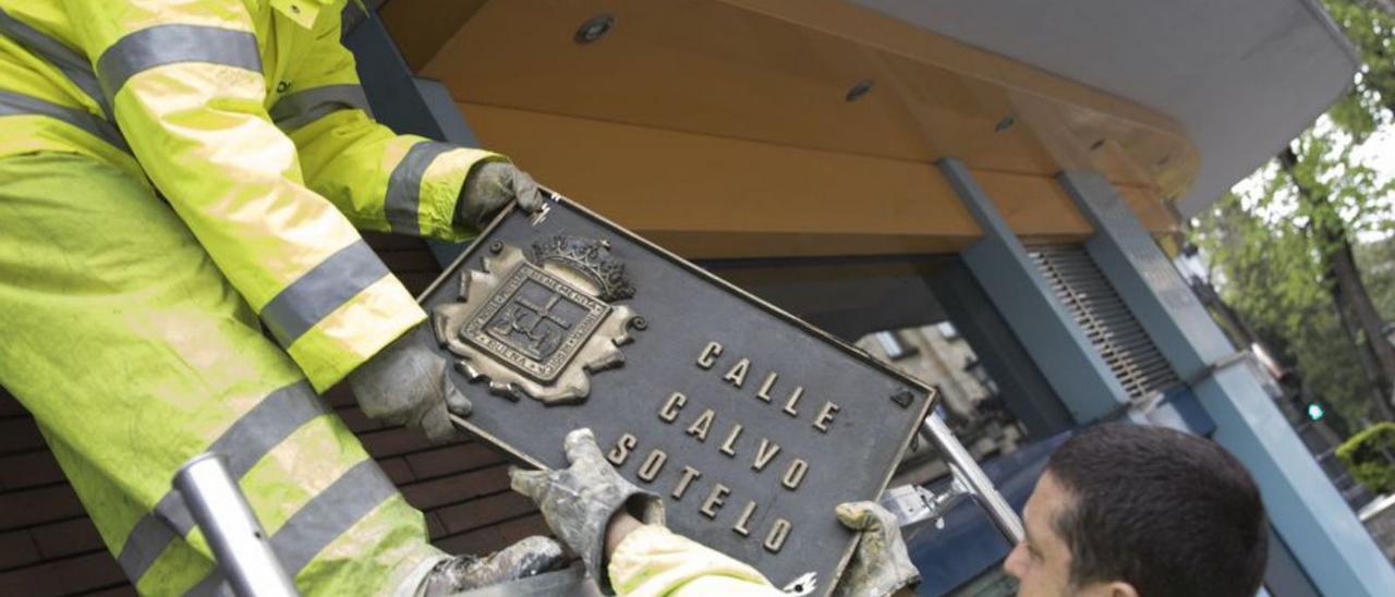 Dos operarios quitan la placa de Calvo Sotelo, en octubre de 2010.