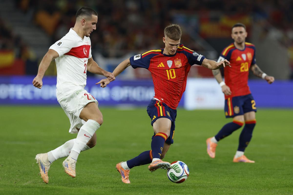 SEVILLA, 18/11/2025.- El delantero de la selección española Dani Olmo (c) controla el balón ante el delantero de Turquía Deniz Gul (i) durante el encuentro correspondiente a la fase de clasificación para el Mundial 2026 que disputan hoy martes España y Turquía en el estadio de La Cartuja, en Sevilla. EFE / Julio Muñoz.