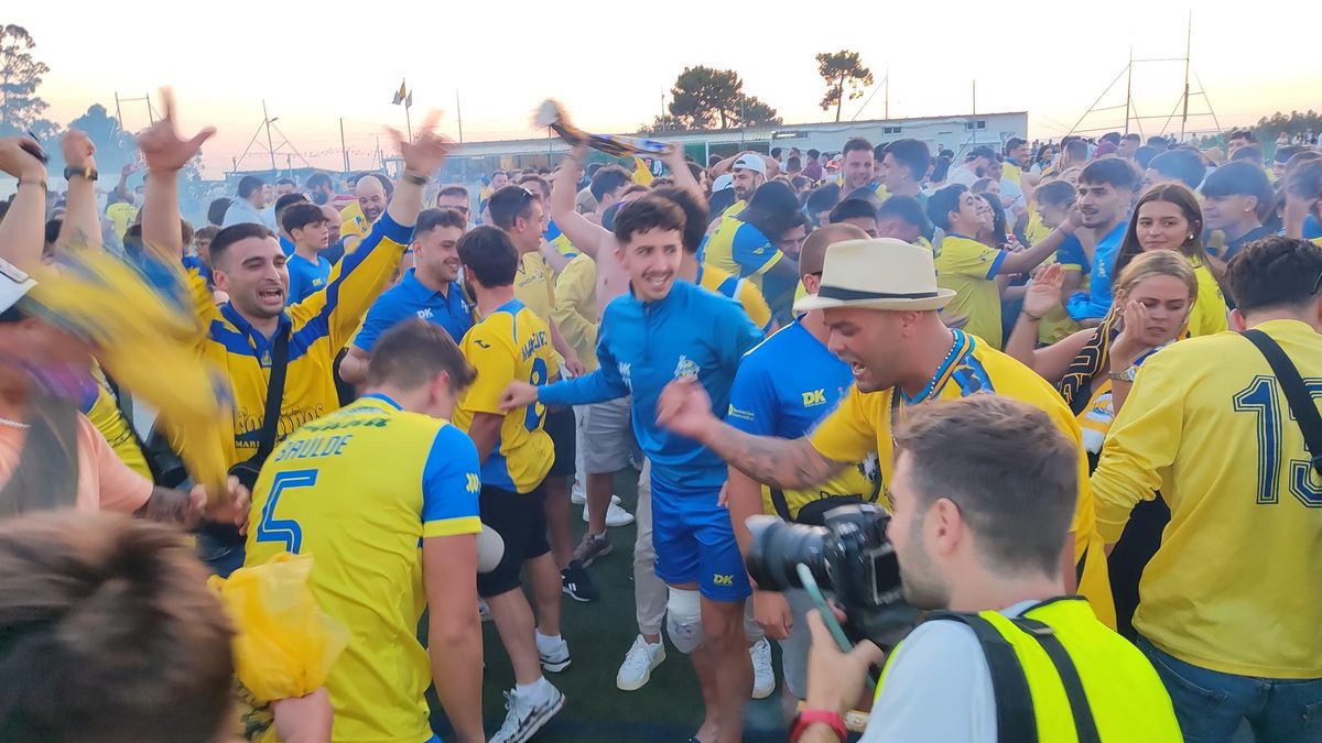 Jugadores y aficionados del Cambados celebran el ascenso a Tercera RFEF sobre el césped de As Laxes.