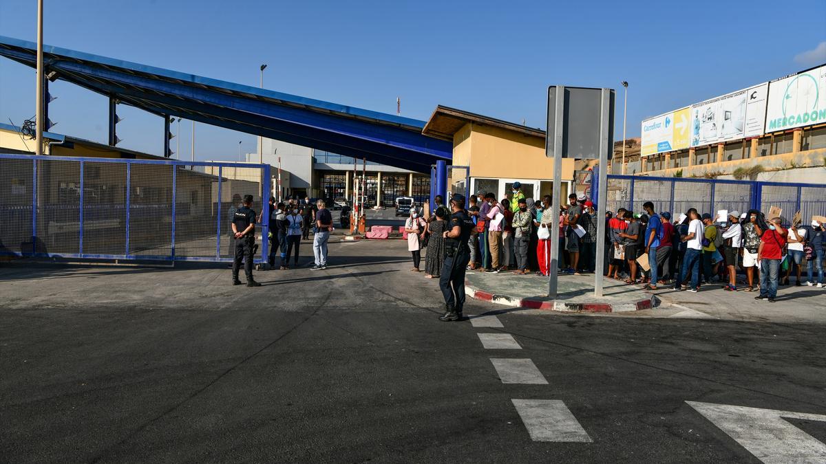 Archivo - Agentes de Policía supervisan a cientos de personas, la mayoría marroquíes, que guardan cola en la frontera del Tarajal que separa Ceuta de Marruecos el 3 de agosto de 2021