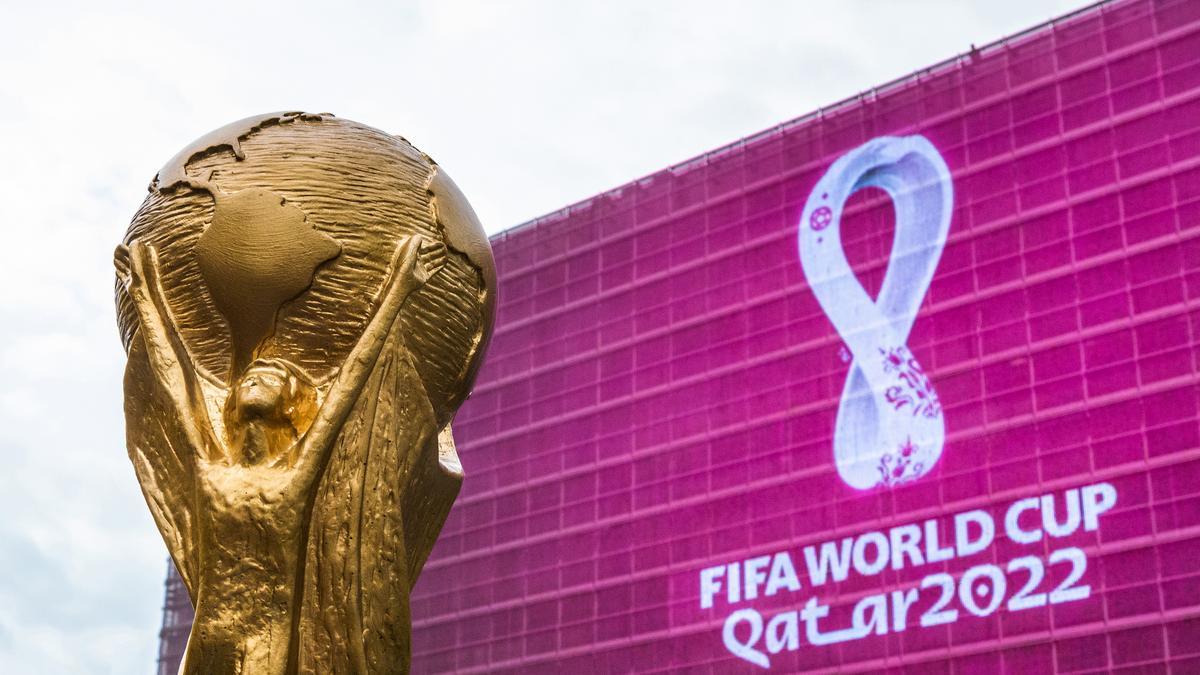 Trofeo de la Copa del Mundo junto a uno de los estadios de Catar 2022.