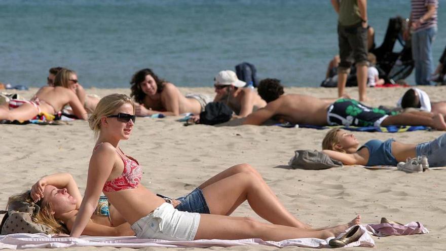 Varias personas toman el sol en un playa.