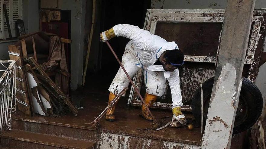 Un hombre limpia las escaleras de su vivienda en Ática.