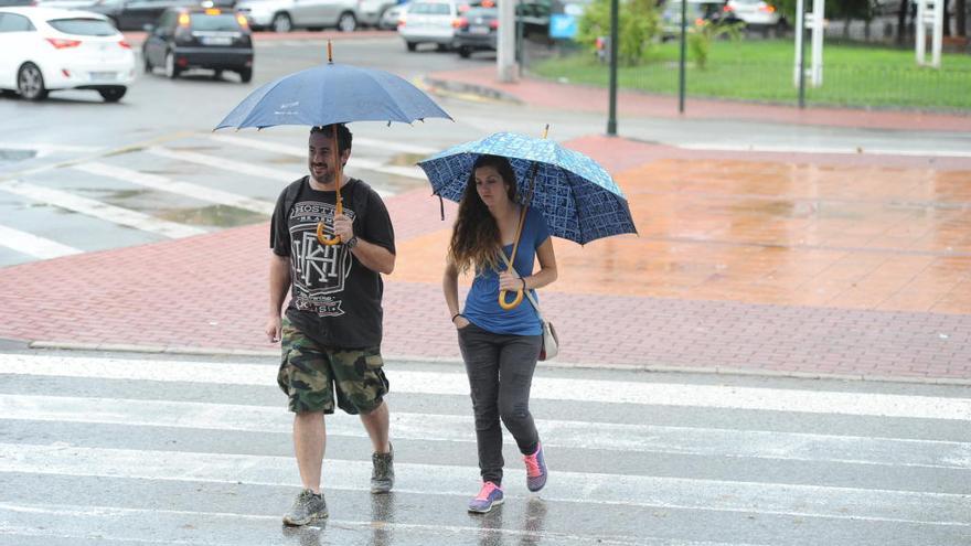 Dos peatones se cubren de la lluvia.