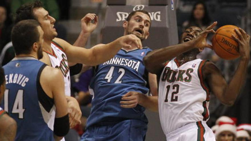 Luc Richard Mbah a Moute de los Bucks de Milwaukee disputa un rebote con Kevin Love de los Timberwolves.