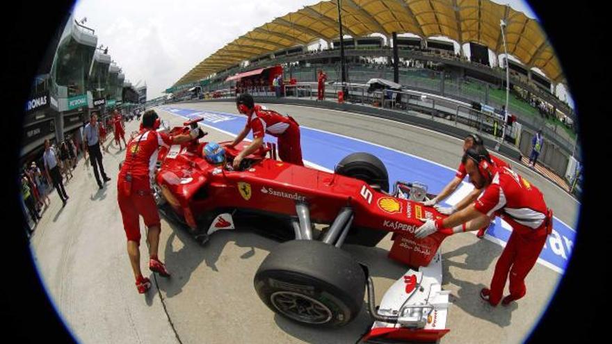 Los mecánicos de Ferrari introducen en el garaje el monoplaza de Fernando Alonso tras la primera sesión libre.