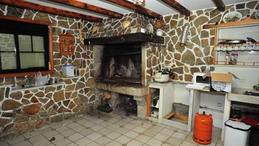 Detalles de lujo y confort  |  La cocina de la planta superior es una de las estancias más agradables de la vivienda próxima a la playa de As Sinas, con sus paredes de piedra encintadas y su gran chimenea. El valor de tasación de esta propiedad es superior a la de Guillán, y en ella también hay detalles sofisticados, como la grifería de los baños, una de las más caras del mercado. En Guillán se cree que había un posible zulo.