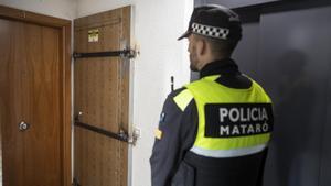 Un policía local de Mataró frente a una puerta blindada por los vecinos para impedir que sea ocupada ilegalmente.
