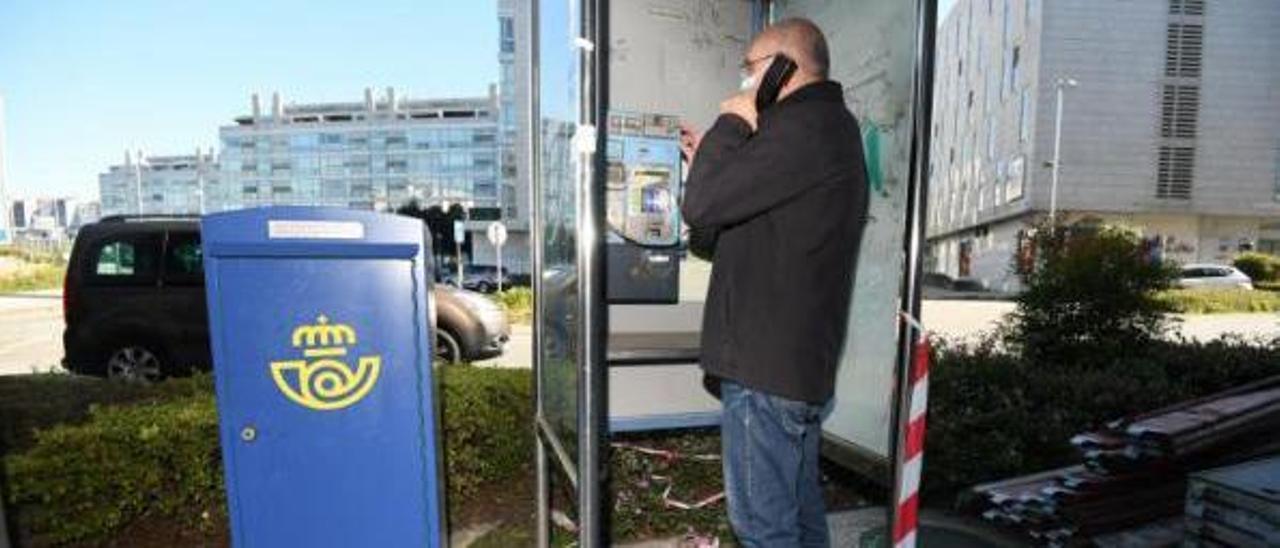 Un pontevedrés comprueba si funciona una vieja cabina de teléfonos en la calle Eduardo Pondal.