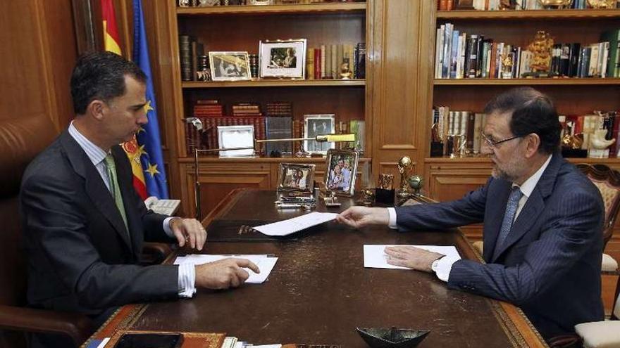 Primer despacho entre Felipe VI y Rajoy. Sobre la mesa, una foto de los príncipes de Asturias con su primogénita, Leonor, recién nacida, y otra del Rey con sus dos hijas. También se ve una réplica de la Copa del Mundo ganada por España.