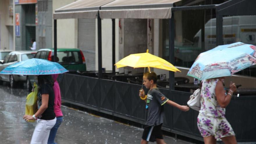 Varios peatones caminan bajo una tormenta de verano.