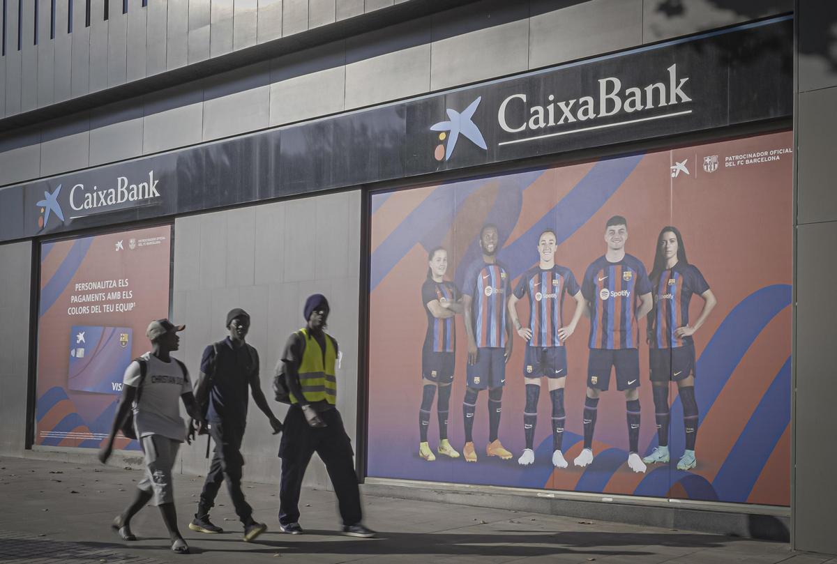 Obreros pasan por delante de un cartel publicitario con los jugadores del Barça