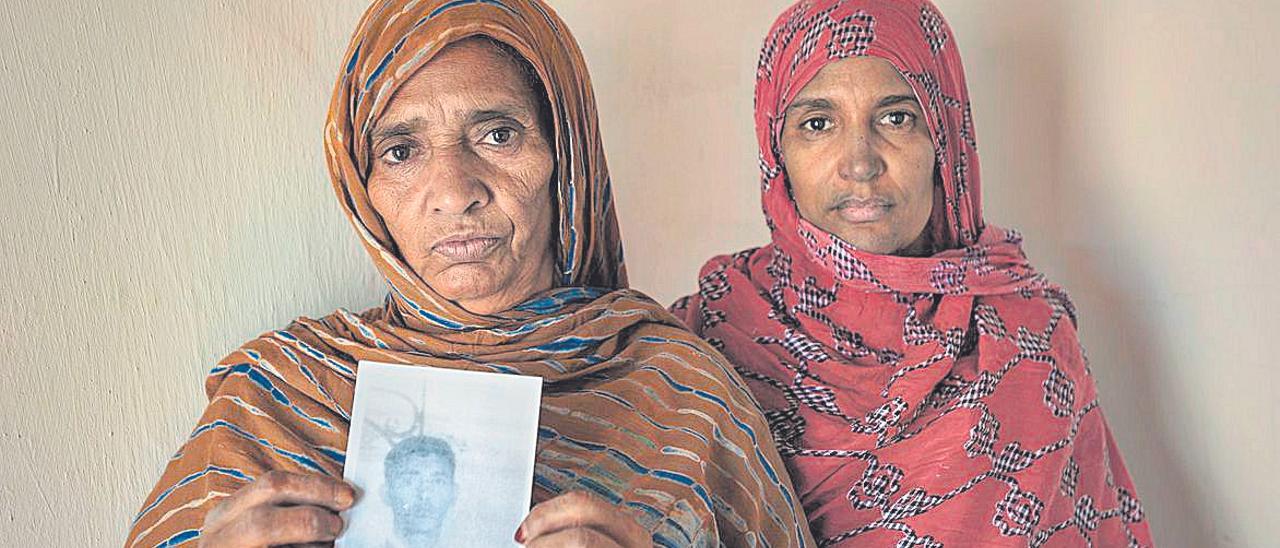 Dos mujeres en el campamento saharaui de Auserd, en octubre de 2016. Muestran el retrato de un familiar desaparecido.