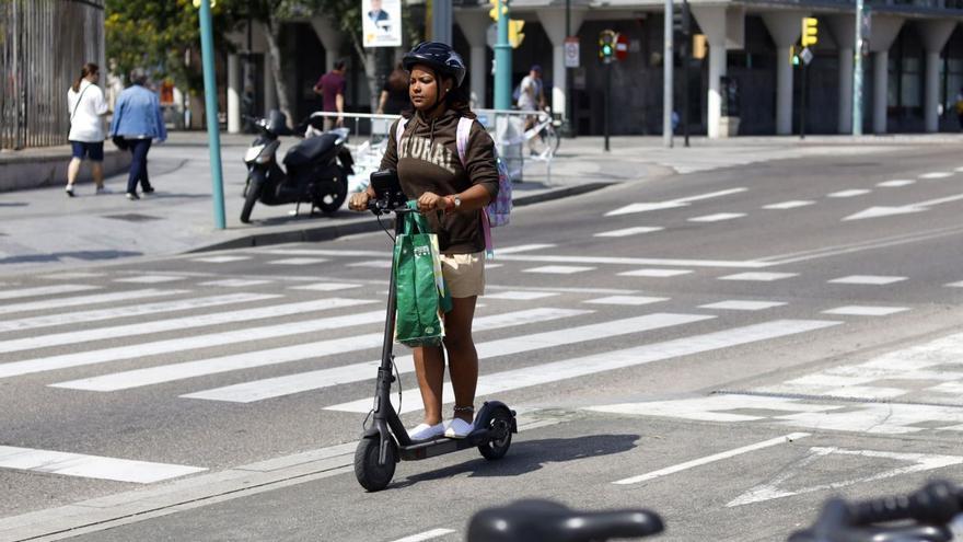 Una usuaria de patinete eléctrico en Zaragoza, con casco circulando por el paseo Echegaray.  | EL PERIÓDICO