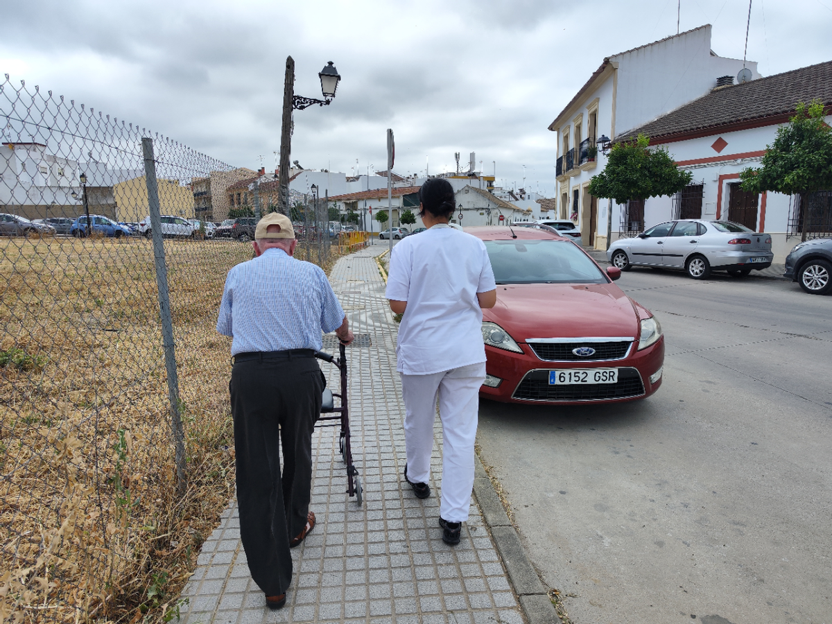 Una auxiliar de ayuda a domicilio acompaña a un hombre mayor, en una imagen de archivo.