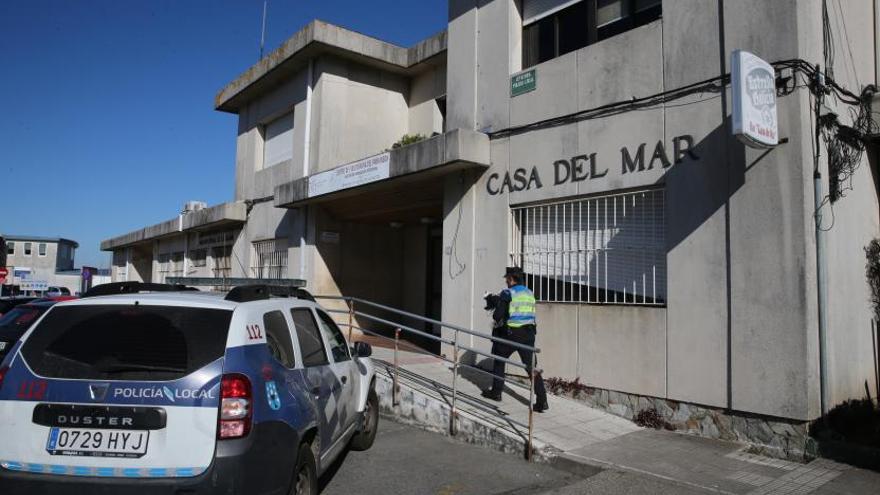 Un coche policial y un agente delante de las dependencias de la Policía Local de Bueu. |   // S.ÁLVAREZ