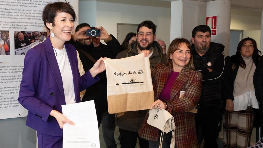 La presidenta de Ons en Loita, María José Pérez (dcha), entrega ayer una bolsa diseñada por los vecinos de la isla y con el lema “O sol por riba da Illa”.