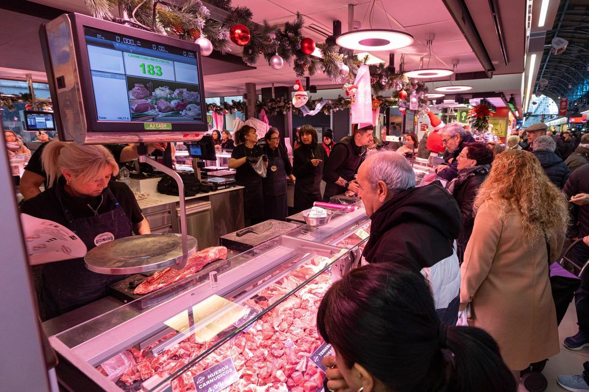 Varios ciudadanos siendo atendidos por una carnicera en un puesto del Mercado Central de Zaragoza
