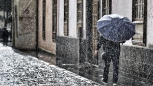 Persona protegiéndose de la lluvia con un paraguas.