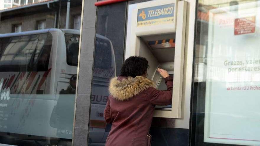 Una mujer realiza una operación en un cajero automático en el centro de Bueu. // Gonzalo Núñez