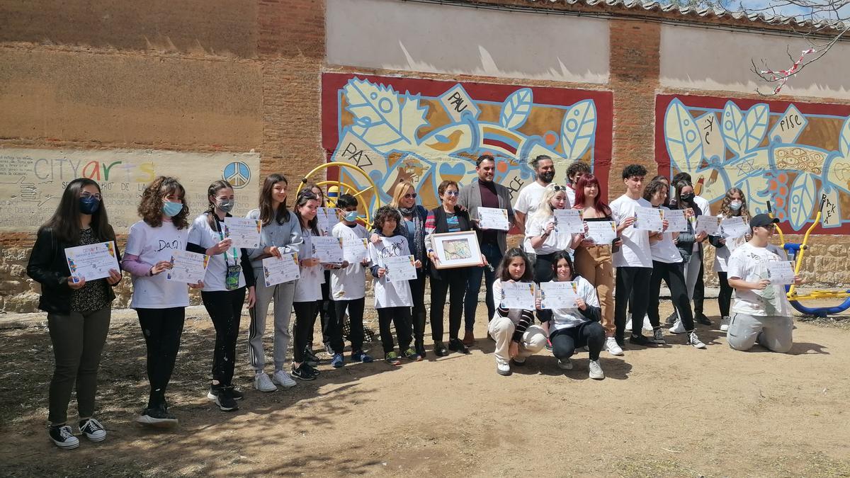 Autoridades y responsables del proyecto posan con los jóvenes que han creado el mural por la paz