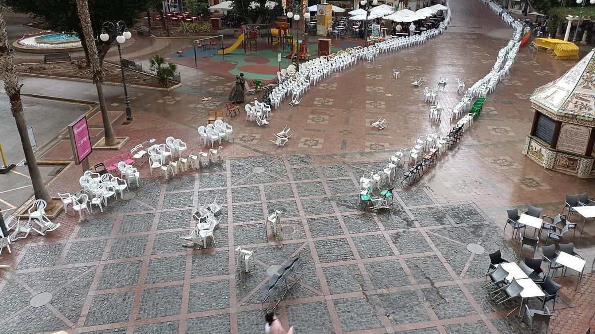 Fuertes rachas de viento arrastran las sillas distribuidas para presenciar la procesión por el medio de la plaza.