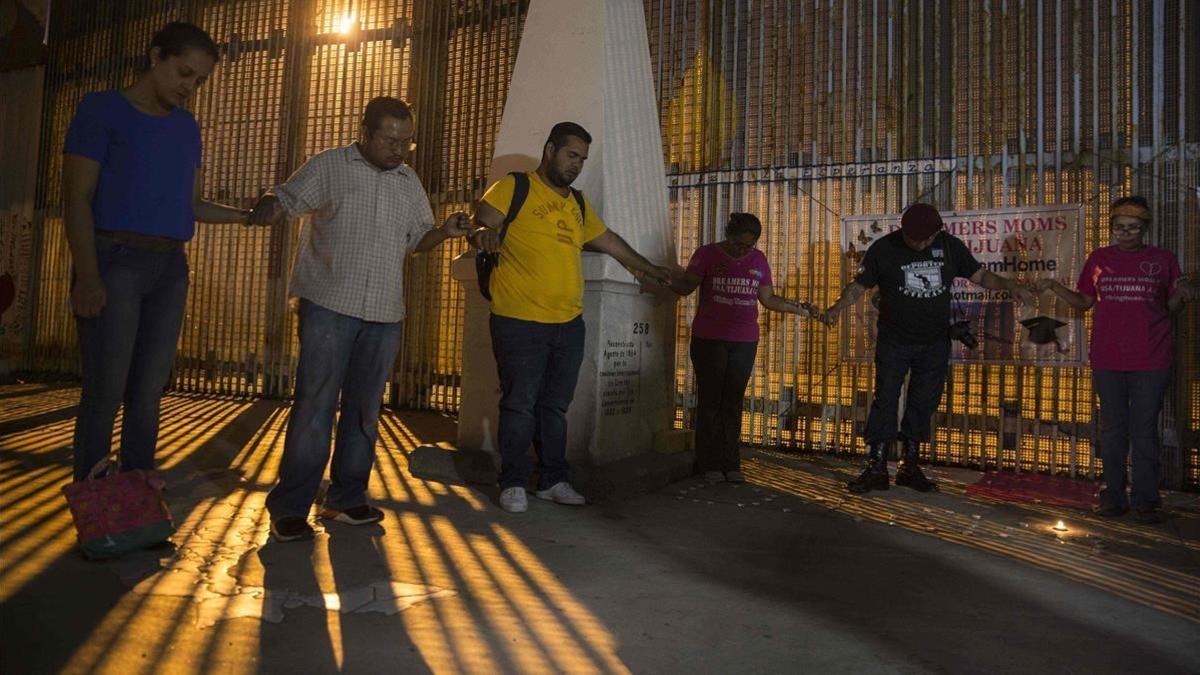 Activistas rezan junto al muro entre México y EEUU durante una protesta contra la posibilidad de deportación de 'dreamers', en Playas de Tijuana (Baja California, México), el 4 de septiembre.