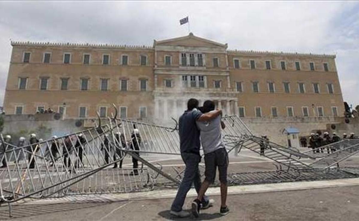 Dos manifestants caminen davant del Parlament grec durant els enfrontaments.