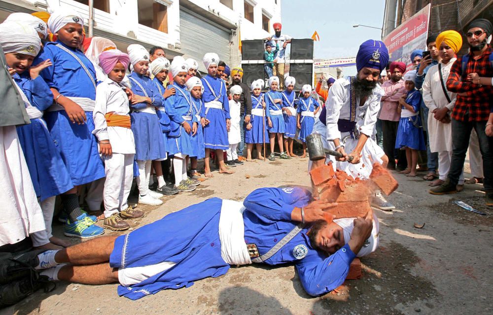 A Nihang or Sikh warrior uses a hammer to break ...