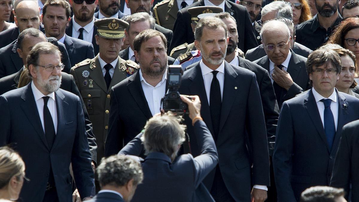 El Rey, junto al 'president', Carles Puigdemont; el vicepresidente del Govern, Oriol Junqueras, y el presidente del Gobierno, Mariano Rajoy, en el minuto de silencio del pasado viernes por las víctimas de los atentados.