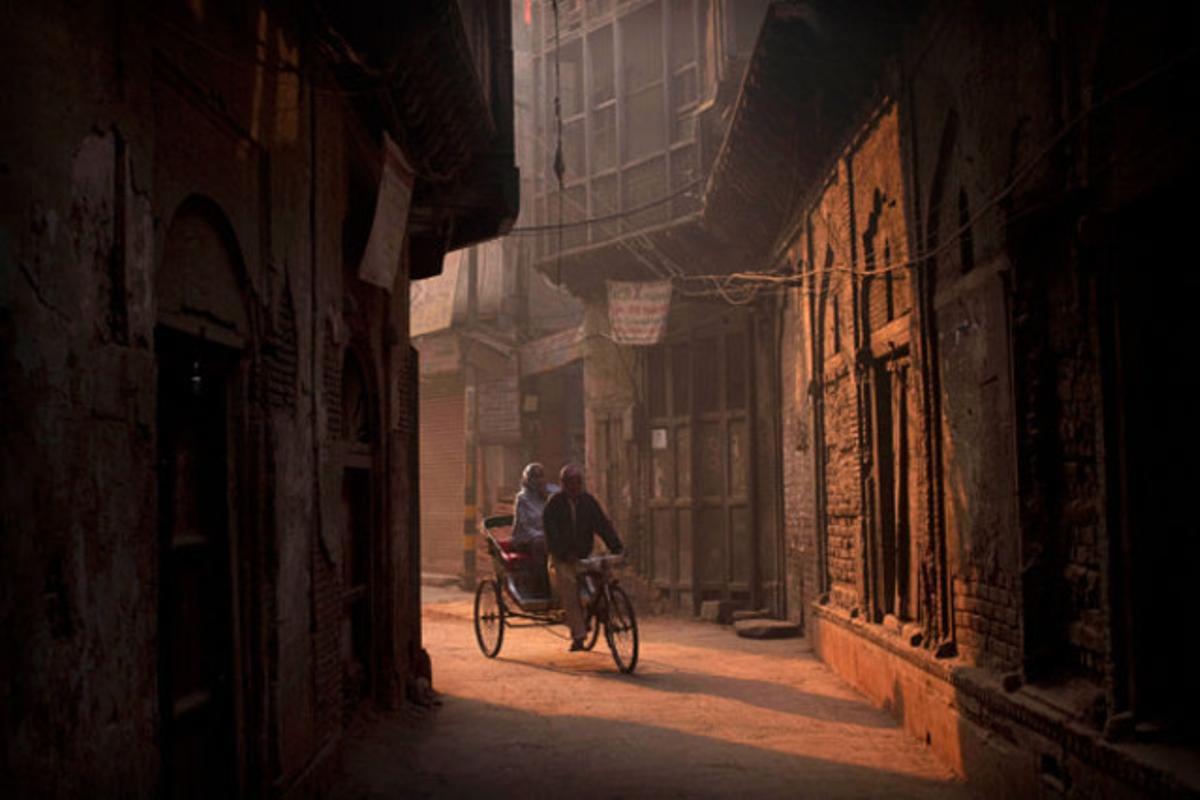 Un conductor de ’ricksaw’, el transport públic més utilitzat pels indis, porta a una dona pels vells carrers de Nova Delhi.