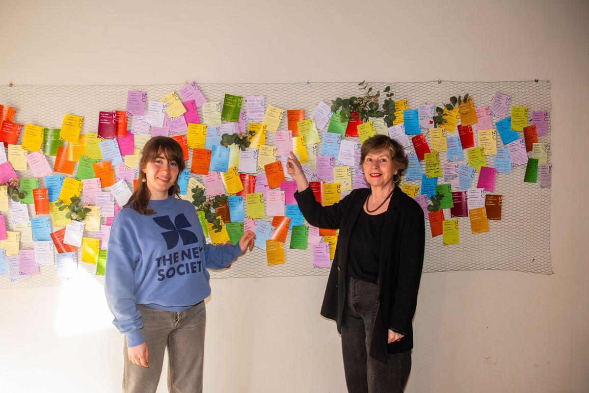 Esther Gómez y su hija, en Moito Conto con el mural con recomendaciones para el día del libro