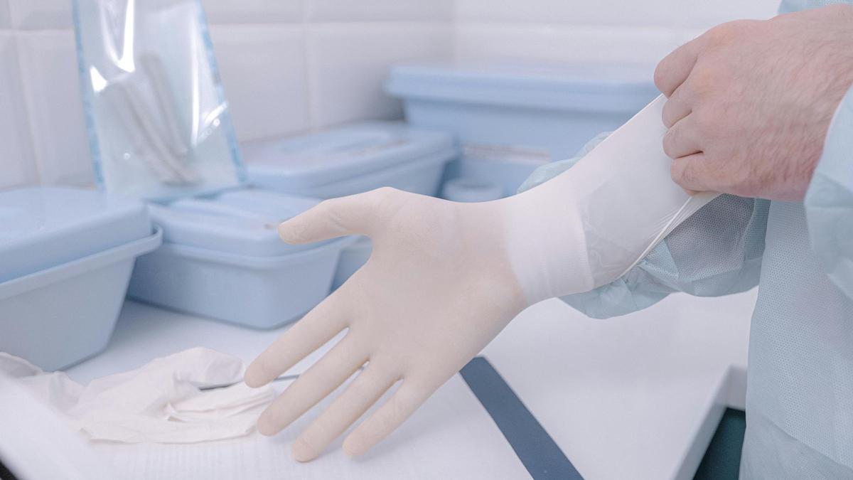 Un profesional sanitario se enfunda unos guantes de látex.
