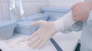 Un profesional sanitario se enfunda unos guantes de látex.