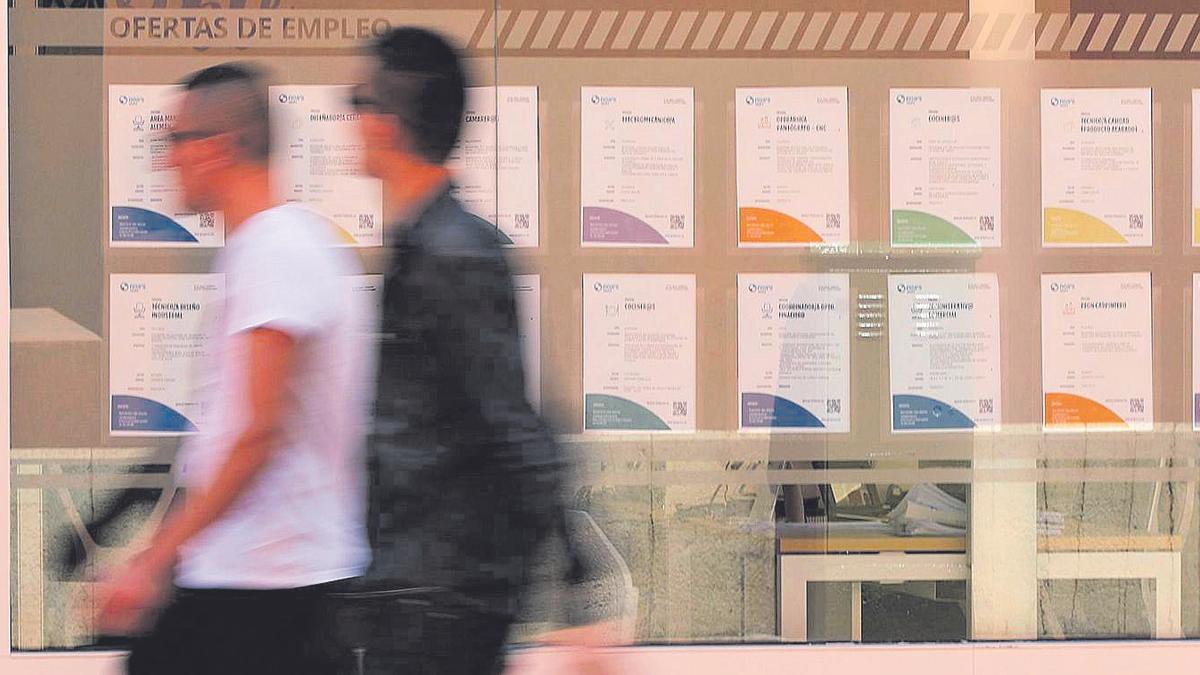 Dos jóvenes pasan frente a una ETT en Castelló.