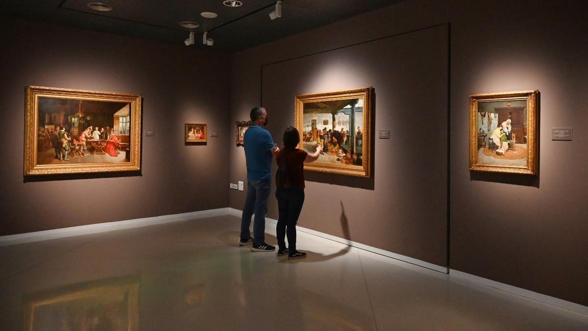 Dos personas observan uno de los cuadros de la colección Pedrera Martínez expuesta en el Muba.