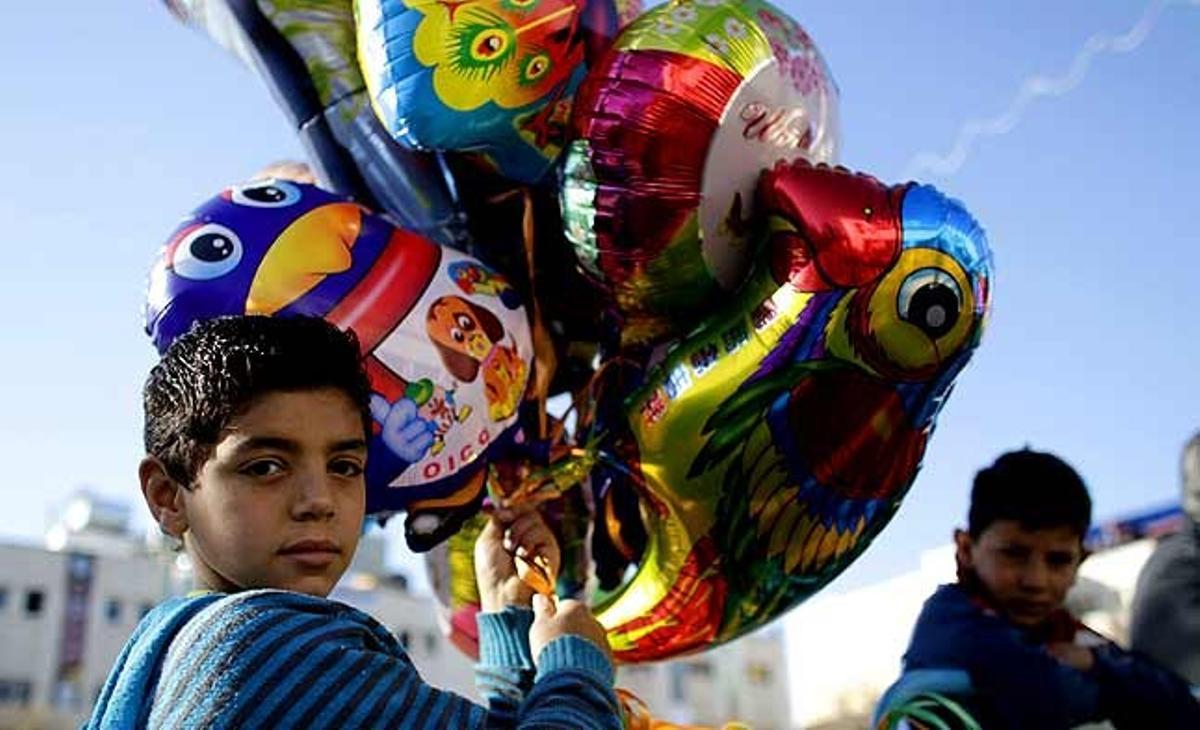 Un nen ven globus a fora de l’Església de la Nativitat, lloc reverenciat com el del naixement de Jesús, a la ciutat cisjordana de Betlem, la vigília de Nadal.