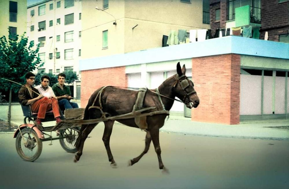 Foto colorejada de forma digital obtinguda d'una en blanc i negre de Salvador Crescenti Miró,o n es veu tres joves conduint un carruatge per un carrer de Salt, prop del grup Verge Maria a inicis dels anys 60