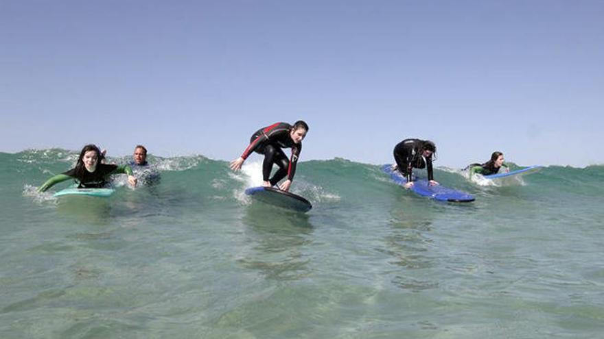 Niños aprendiendo surf en la playa de A Lanzada.