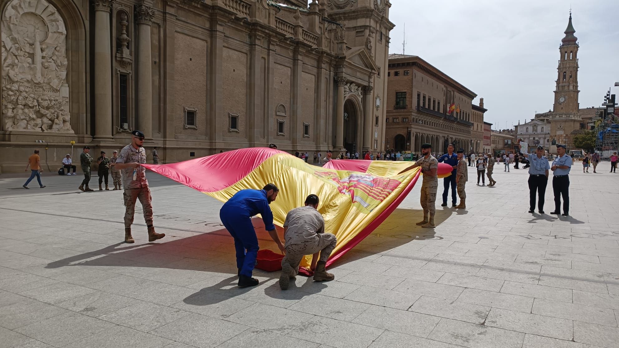 Preparativos para el despliegue aéreo de una bandera de España en la Plaza del Pilar