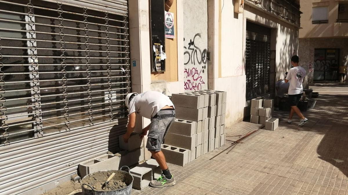 Arbeiter mauern die Zugänge zu dem besetzten Gebäude im Carrer Manacor zu..