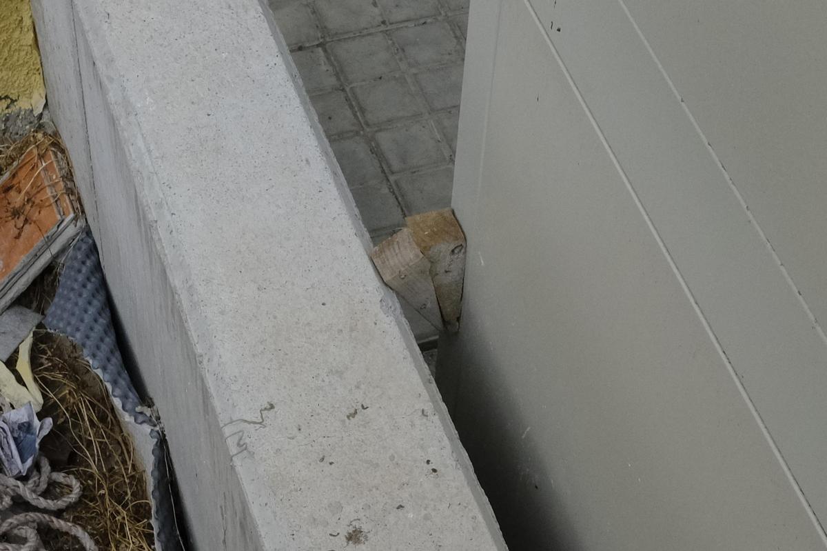 Dos cuñas de madera que están entre la estructura de uno de los ascensores y el muro de un parterre.