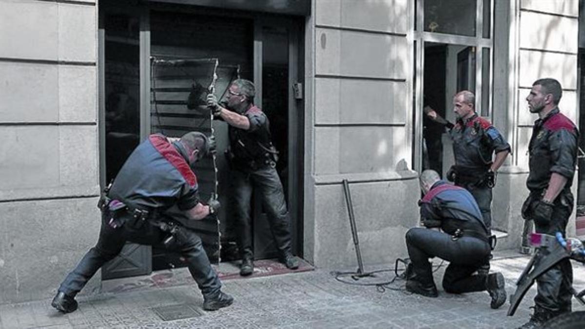 Unos mossos derriban la puerta del club cannábico Hardala en la calle de Bailén de Barcelona, ayer.