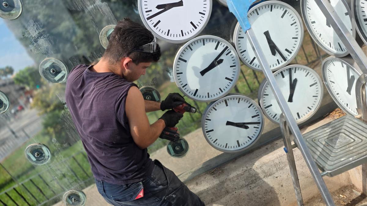 Un trabajador retira los relojes del monumento a las víctimas del metro para repararlos y reponerlos para el próximo viernes.